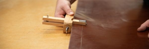 Leatherworker cutting a strap from a piece of leather with a strap cutter